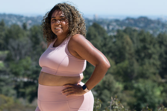 Plus size woman wearing Superfit Hero Superhold Collection sports bra and bike shorts blush.