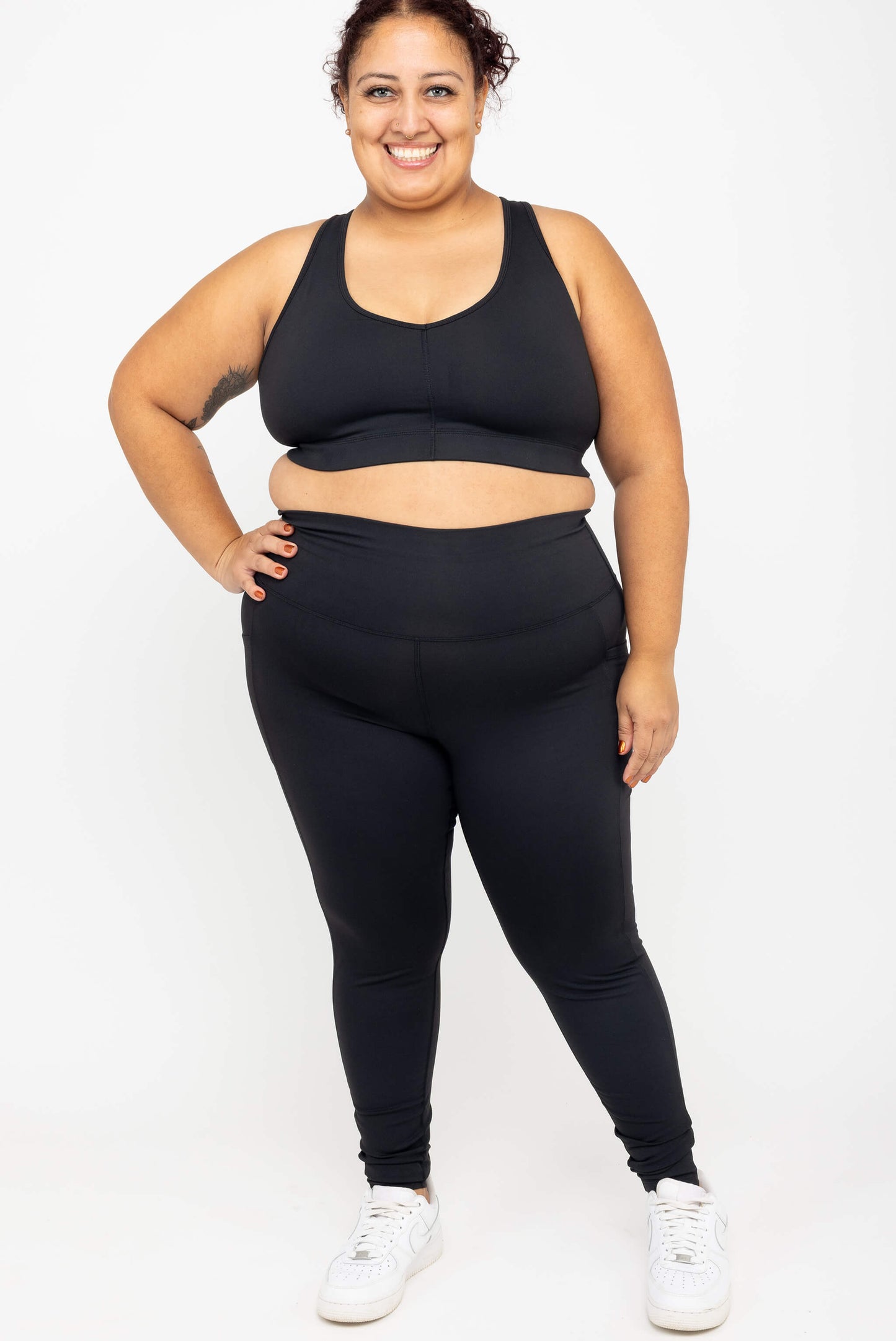 Full body view of model wearing Black Superfit Hero SuperHold™ Pocket Ankle Leggings and matching V-neck sports bra, size 2X