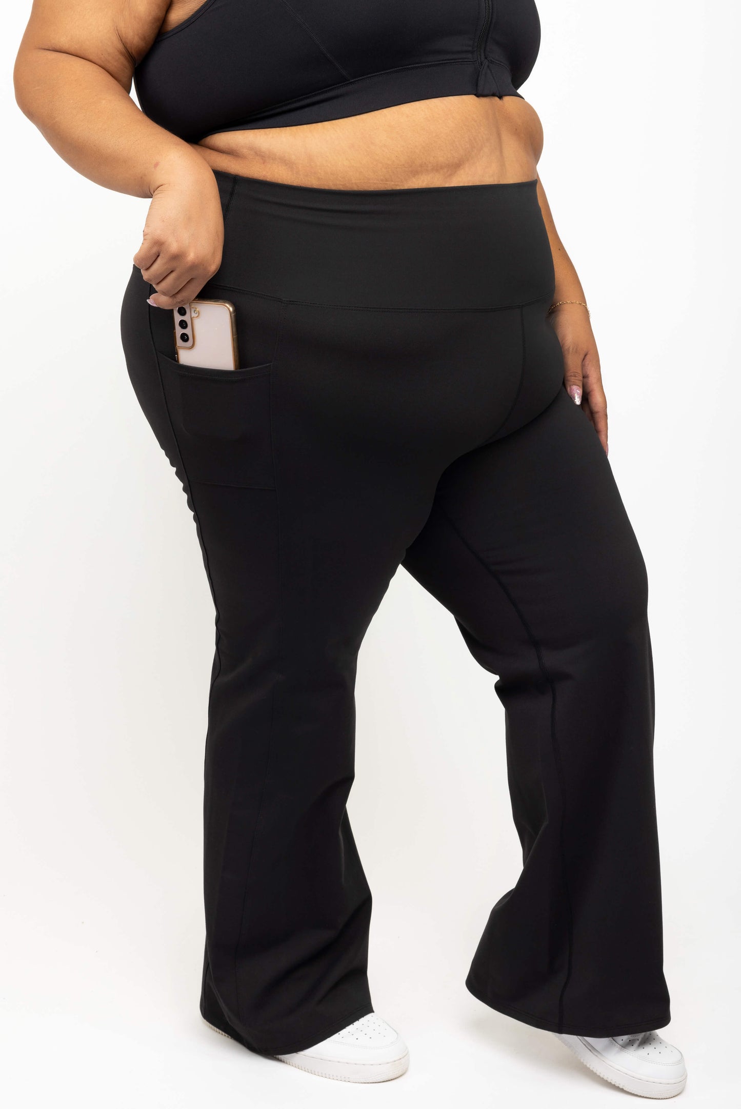 Close up of phone in pocket of Superfit Hero black plus size flare leggings with pockets size 3X