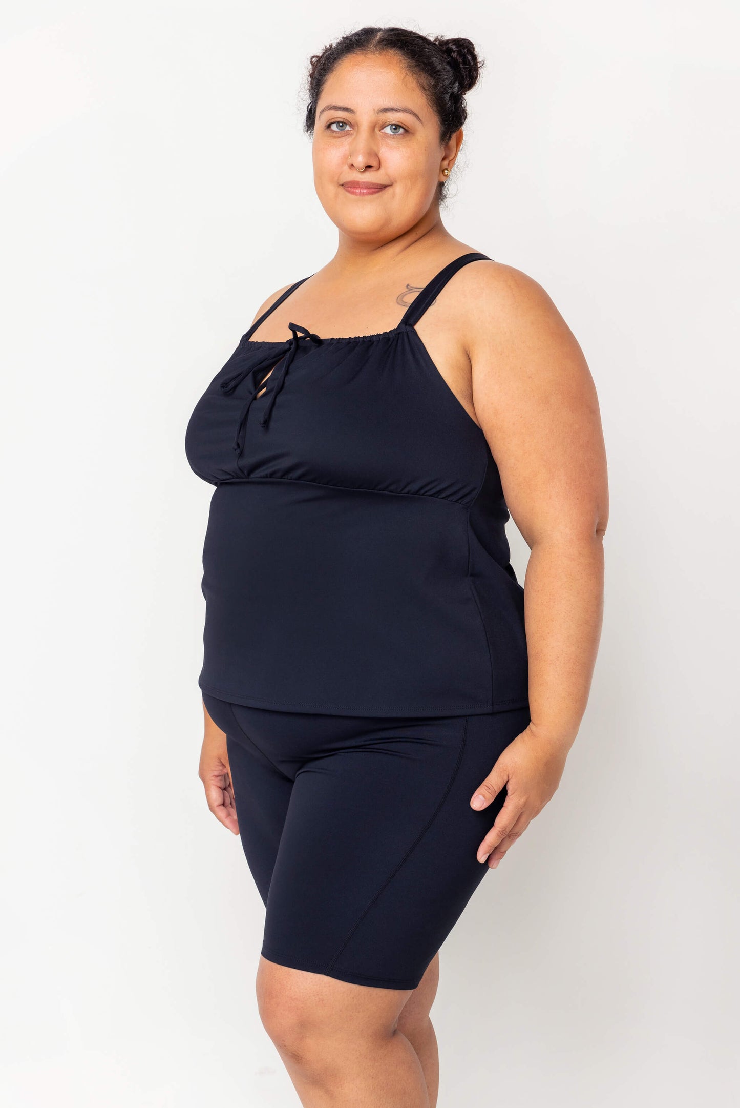Profile view of model wearing black Plus size swim tankini size 2X