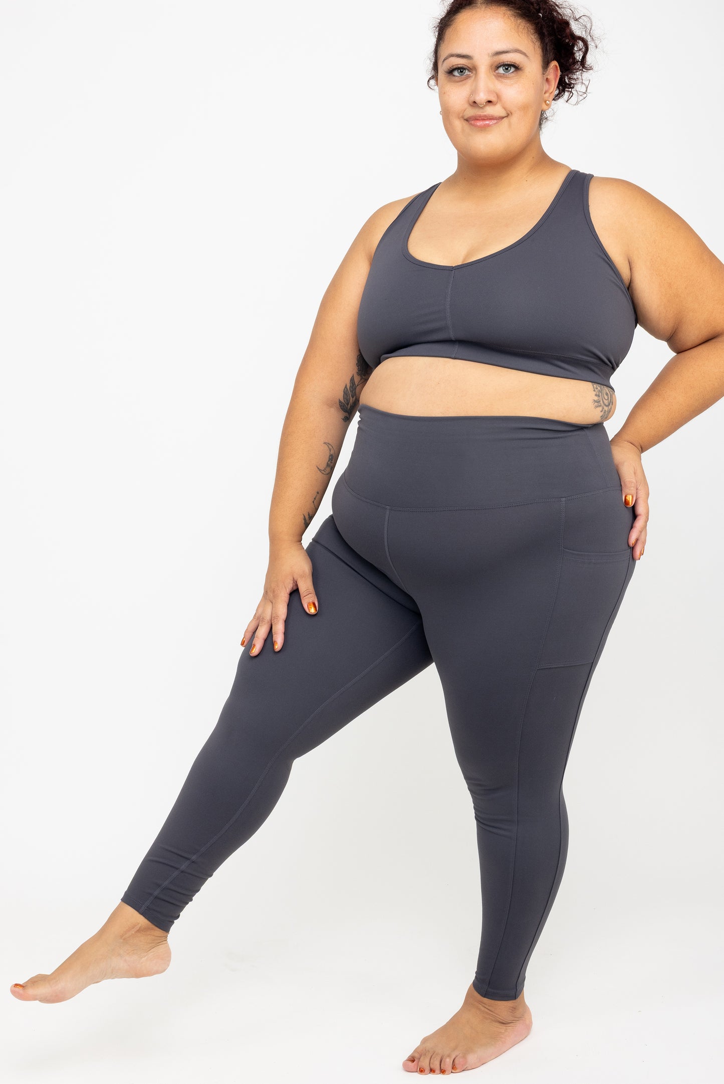Model kicking her leg out wearing Superfit Hero SuperHold™ 7/8 leggings in color Carbon, size 2X
