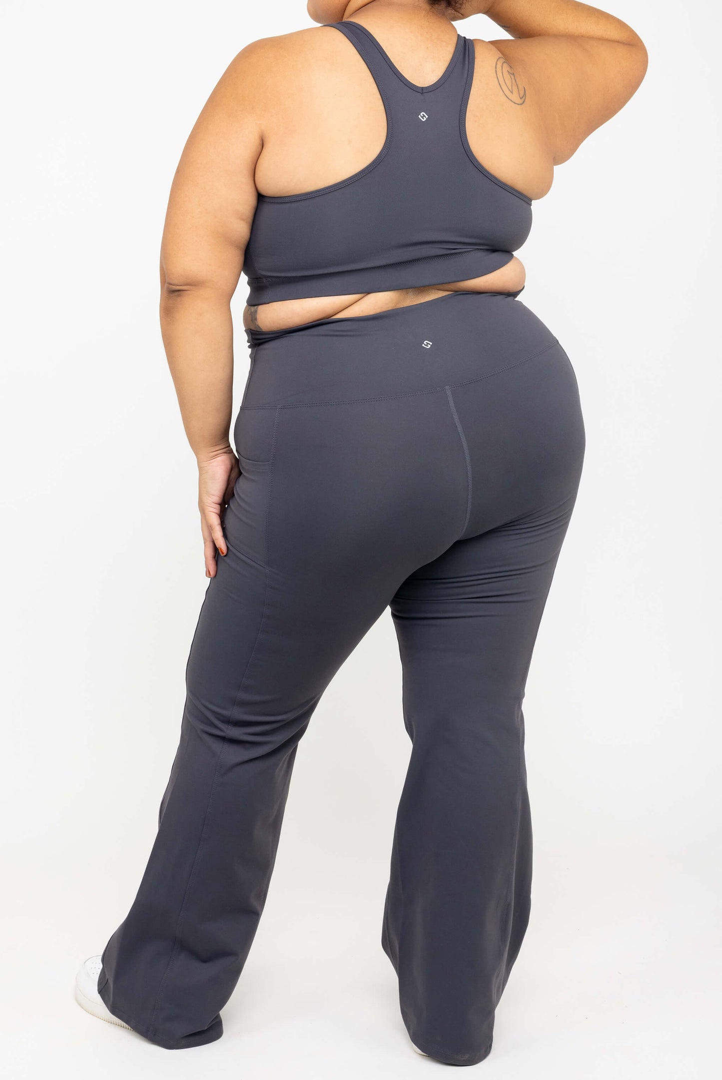 Back view of model wearing SuperHold™ Flare Pocket Leggings in Color Carbon, size 2X with matching V-neck Sports bra
