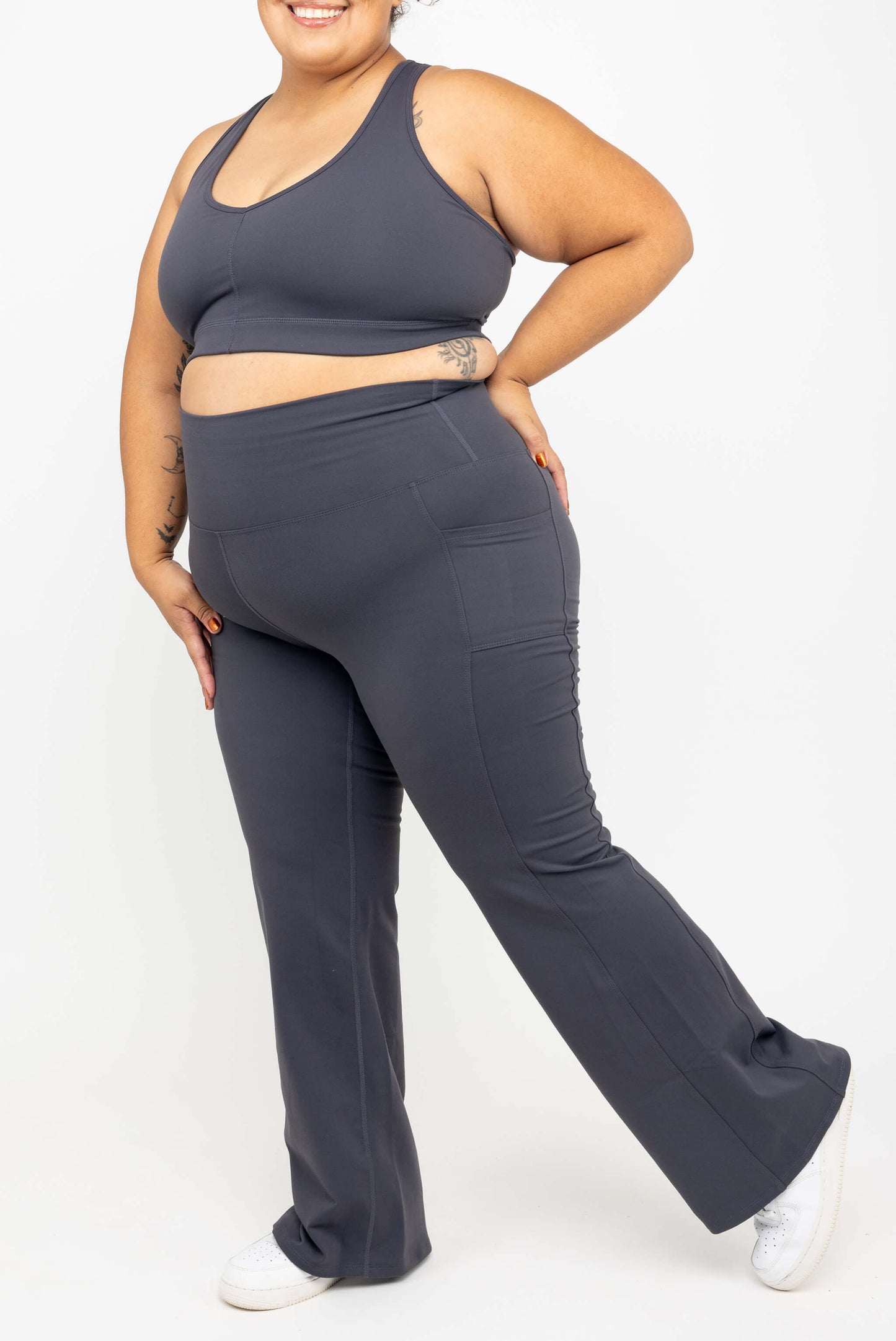 Side view of model wearing SuperHold™ Flare Pocket Leggings in Color Carbon, size 2X with matching V-neck Sports bra