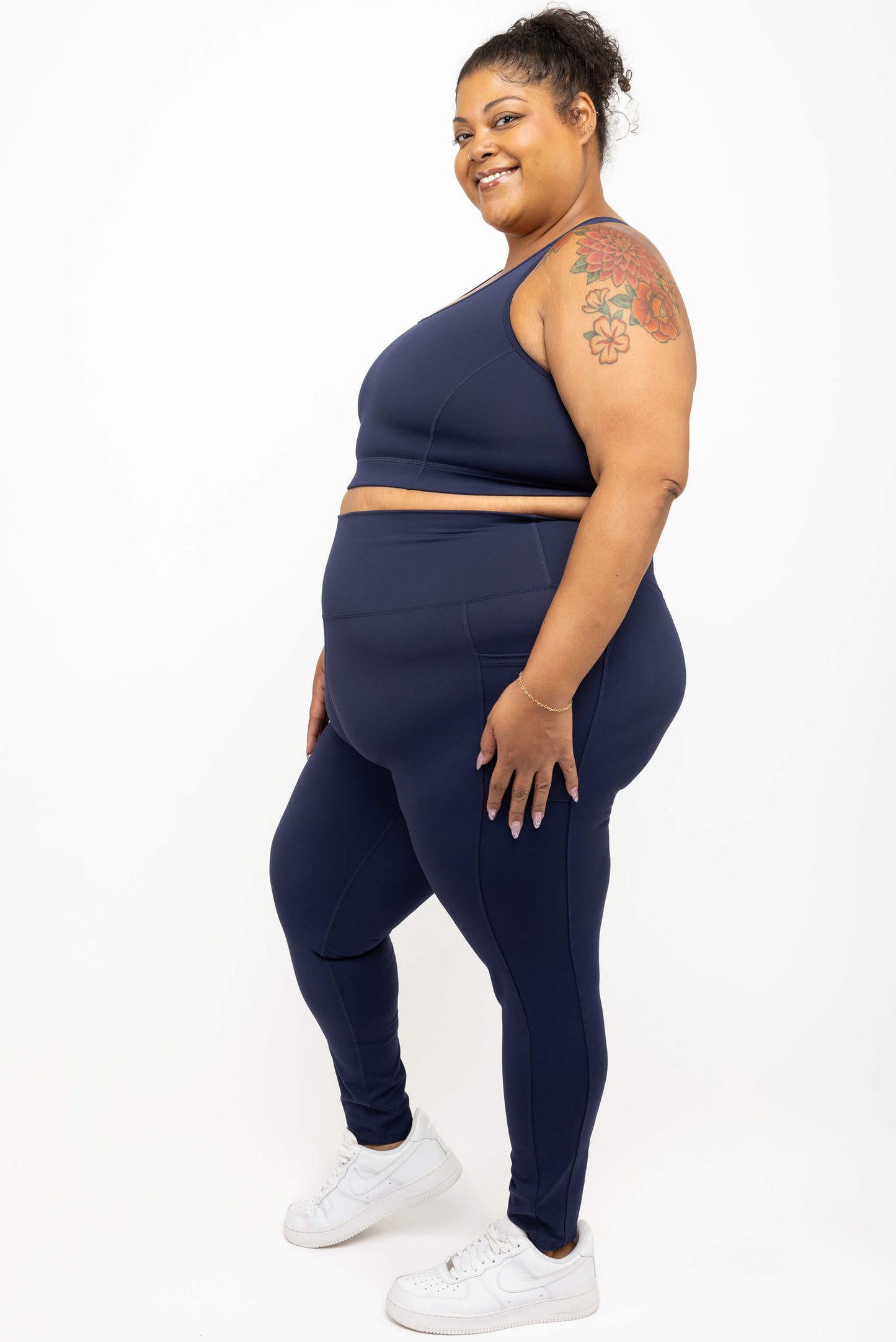 Profile of model wearing Superfit Hero plus size compression leggings with pockets in navy size 3X