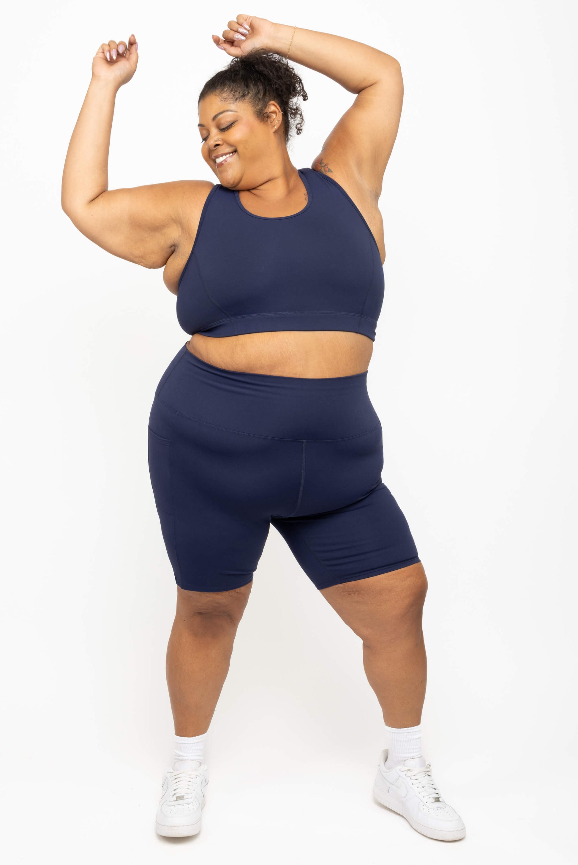 Model dancing while wearing Superfit Hero plus size compression biker shorts in navy size 3X