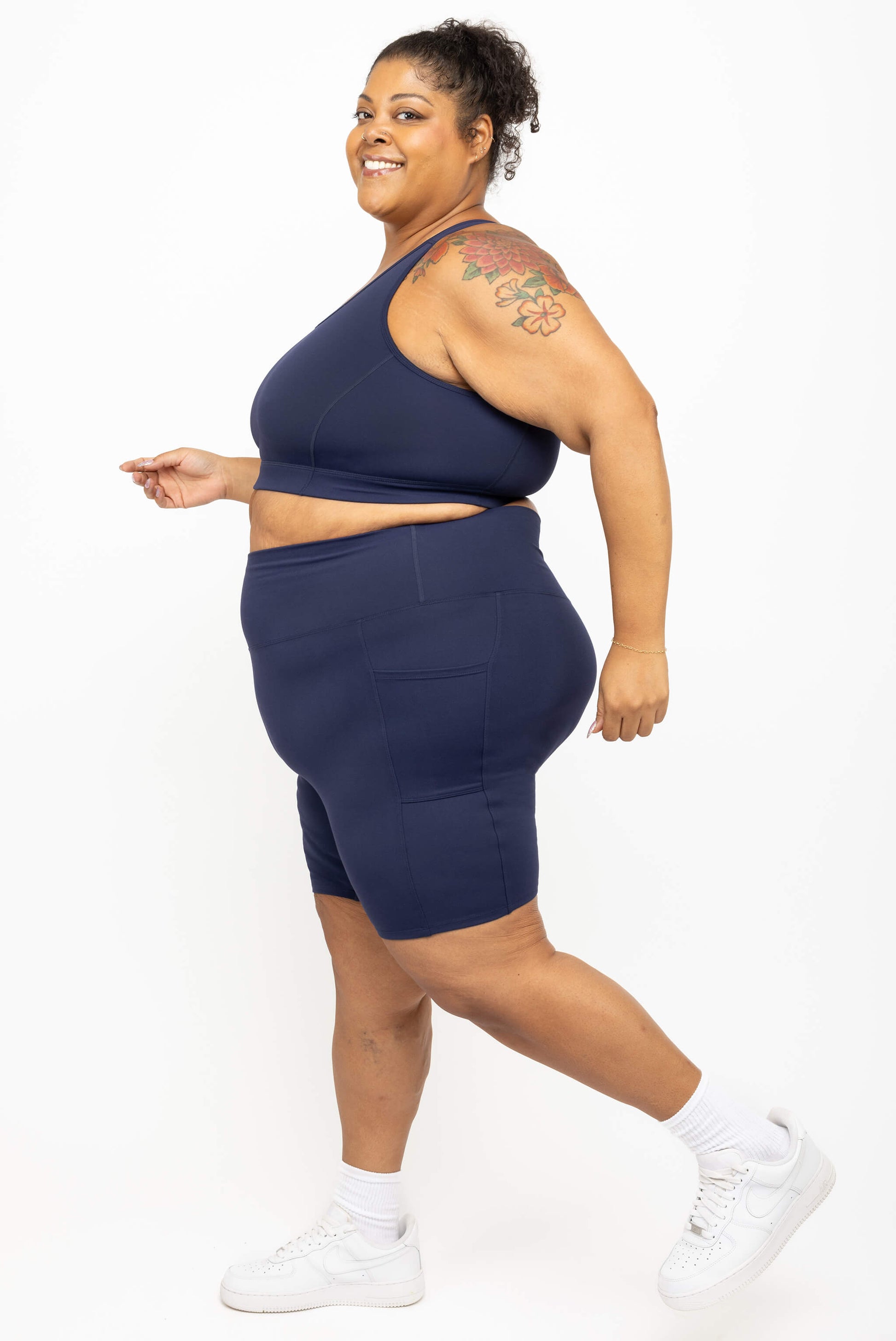 Model walking in Superfit Hero plus size compression biker shorts in navy size 3X