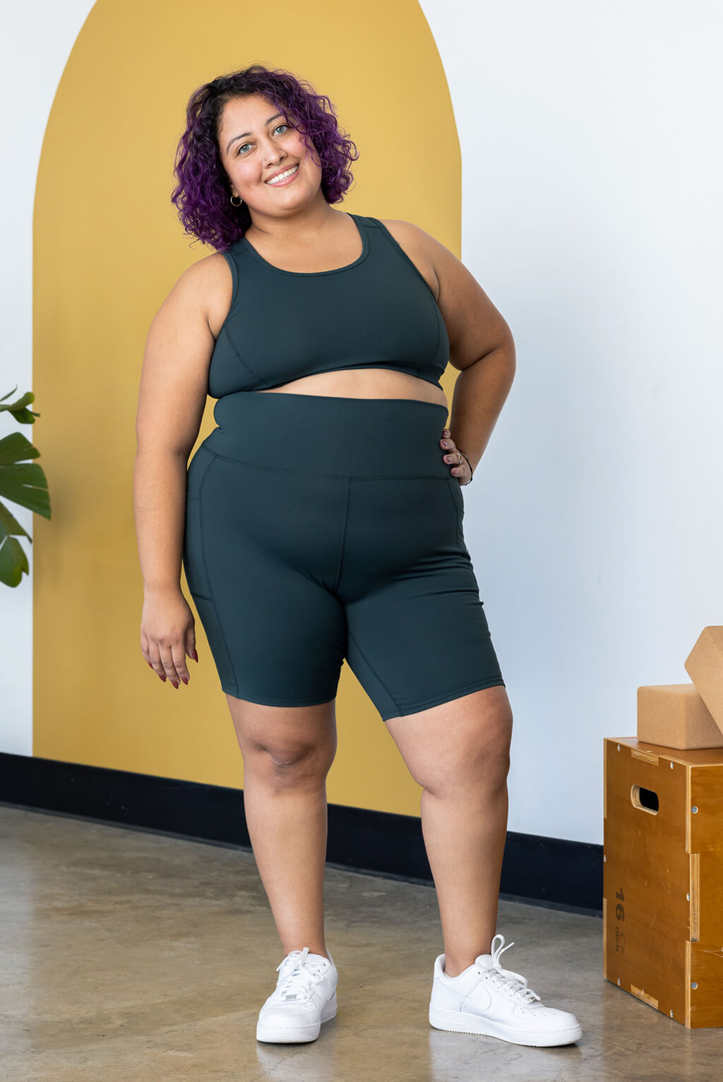 Plus size model posing in evergreen biker shorts with pockets
