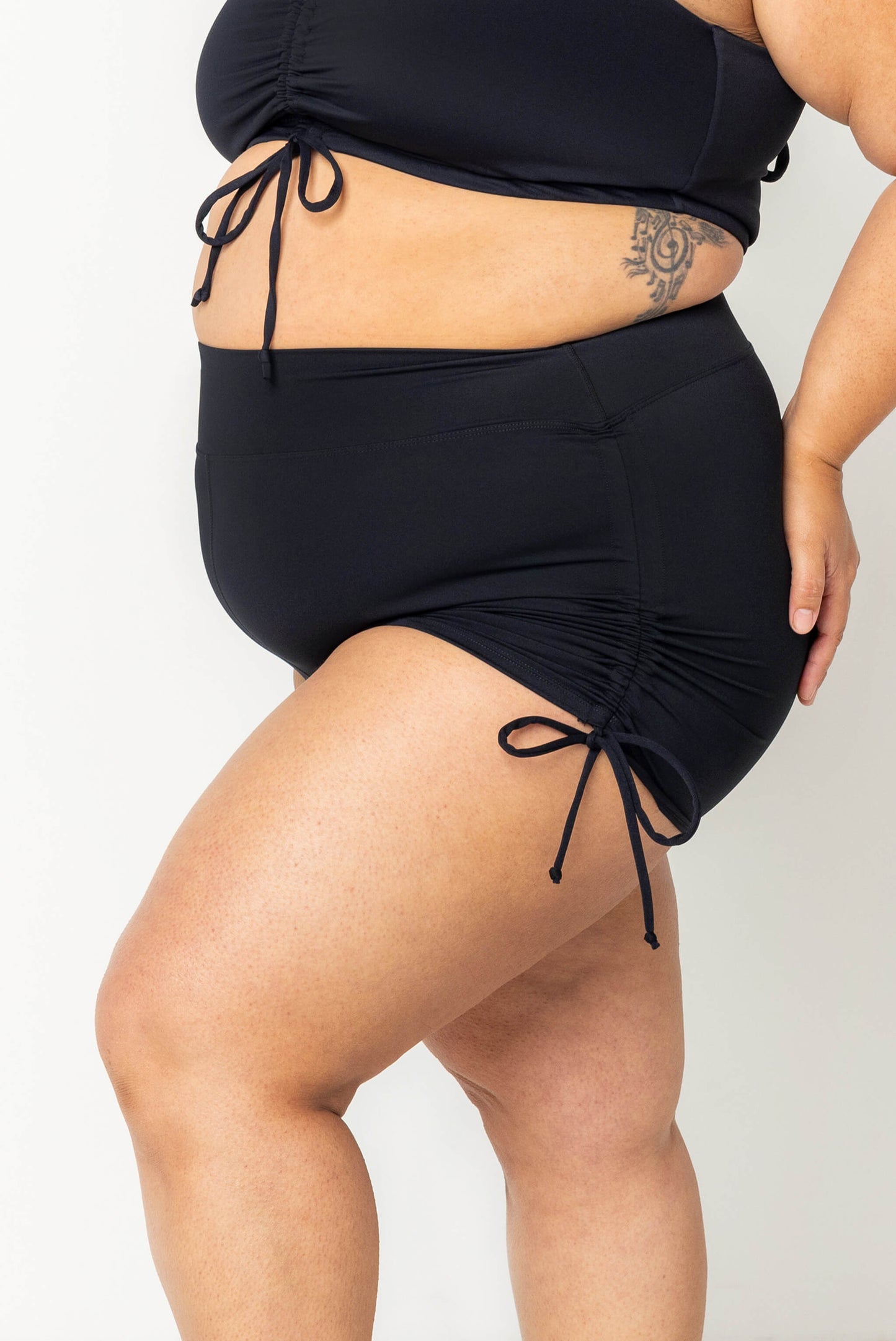 profile view of swim booty shorts with the side cinched up