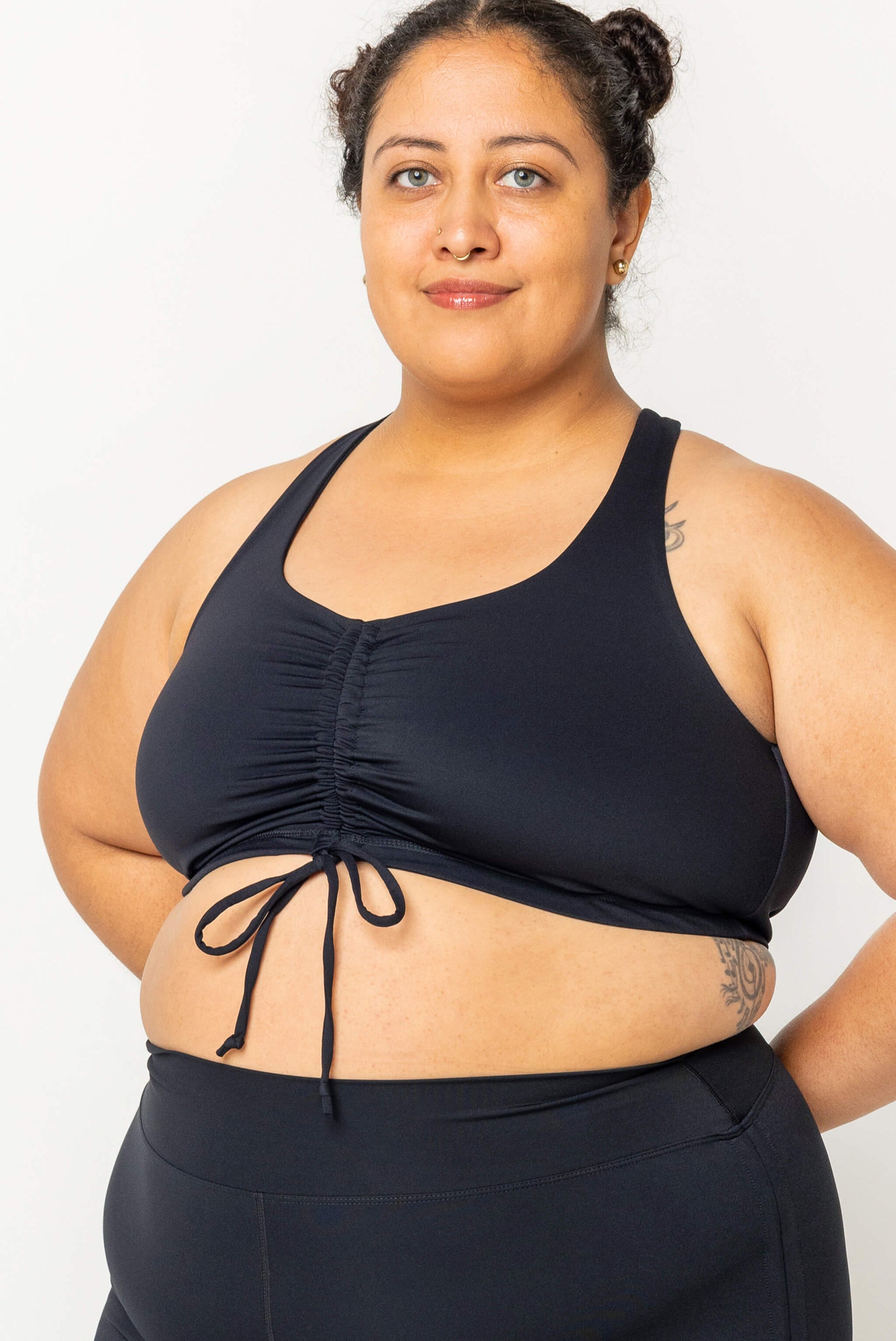 Plus size model wearing black cinched bikini swim top in size 2X