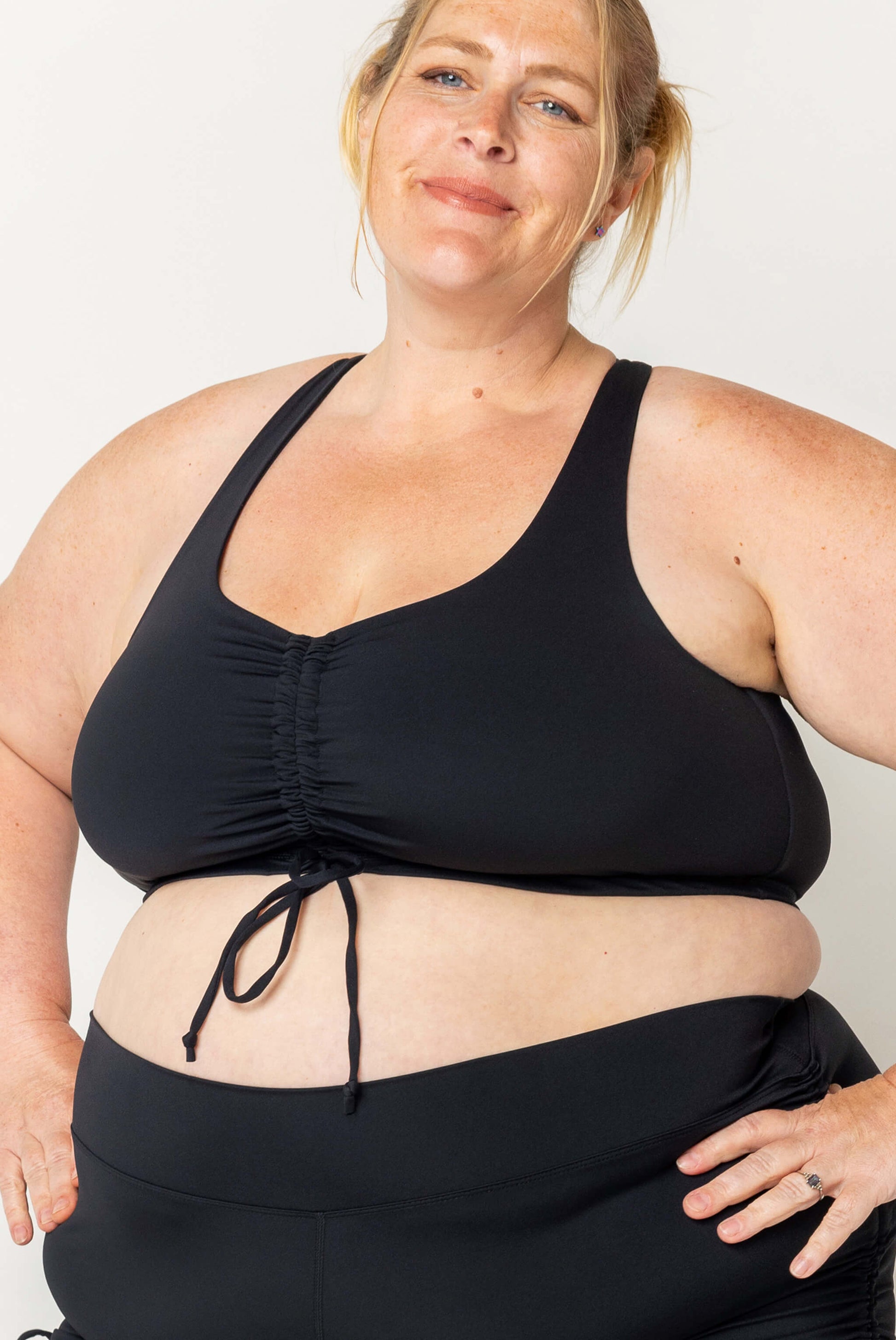 Plus size model wearing black cinched bikini swim top in size 3X