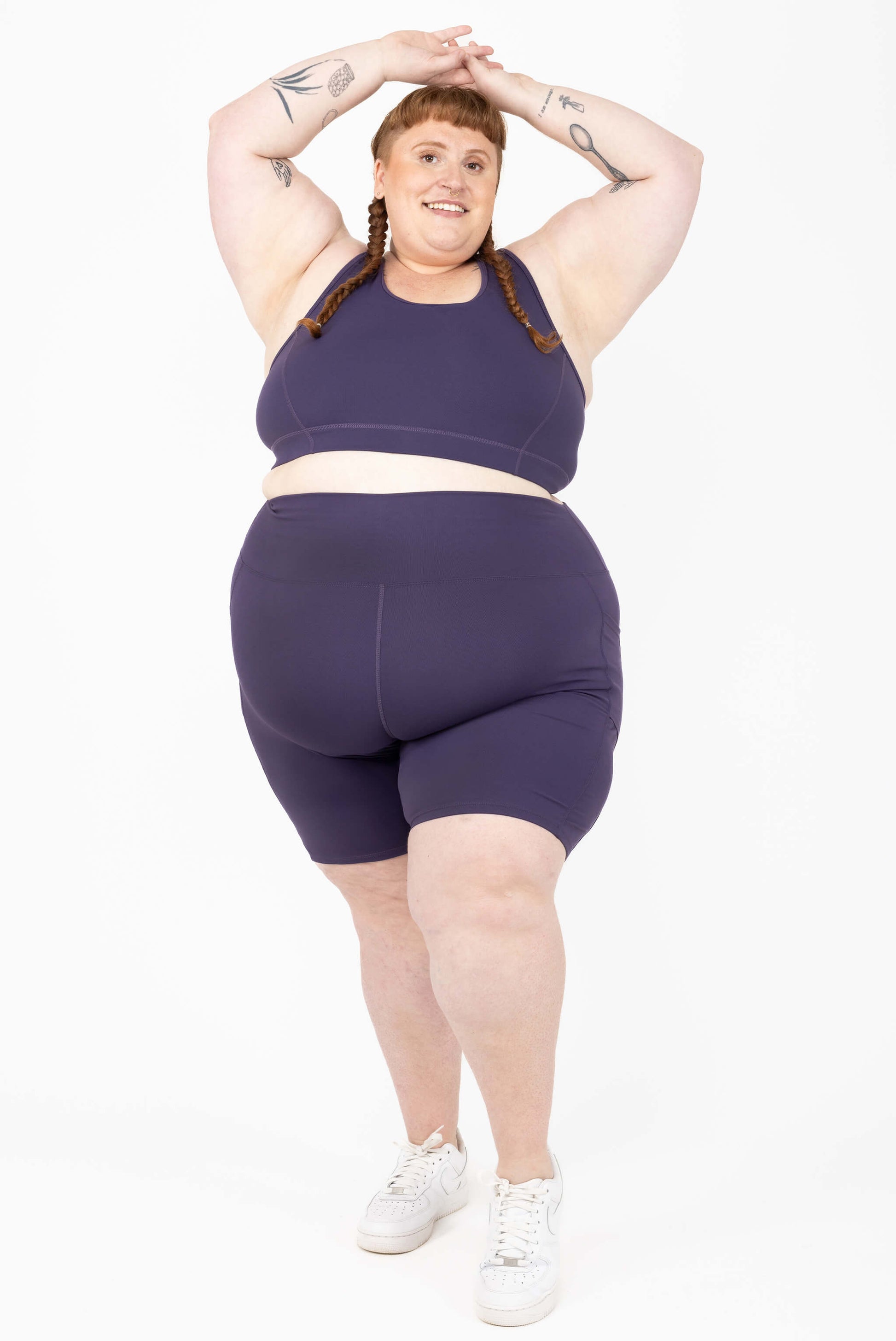 Happy model wearing Plus size 9 inch compression biker shorts size 5X purple
