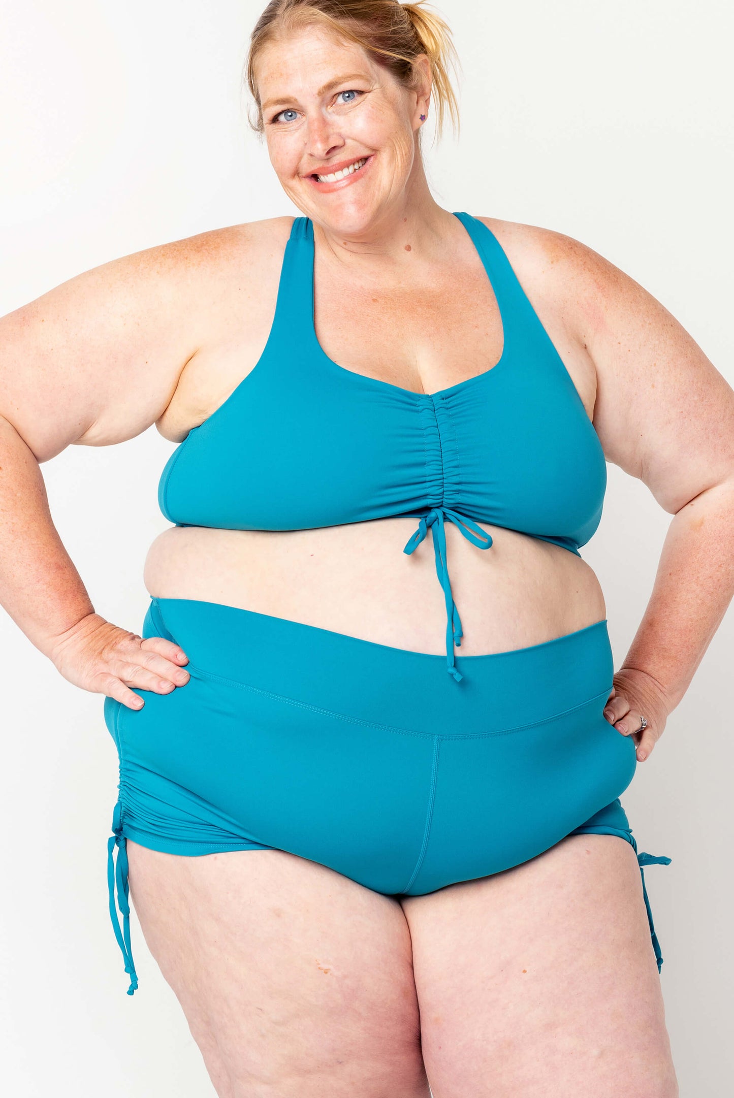 Plus size model wearing teal swim booty shorts in size 4X