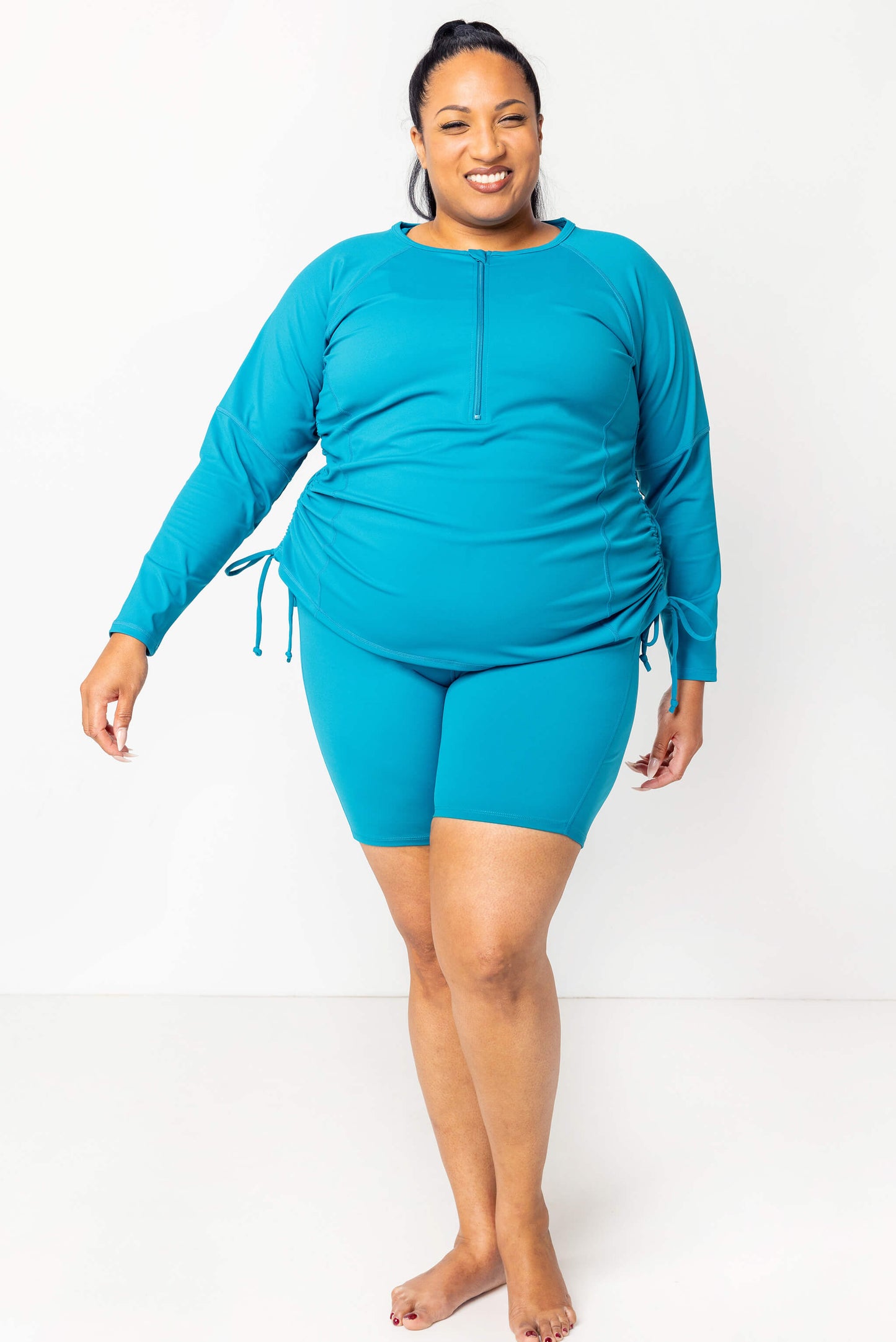 Plus size model full body shot of teal swim rash guard in size 2X