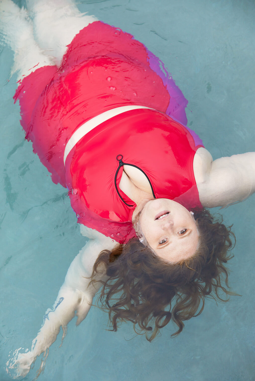 Size 5x model floating in the water wearing colorblock swim shorts and matching top