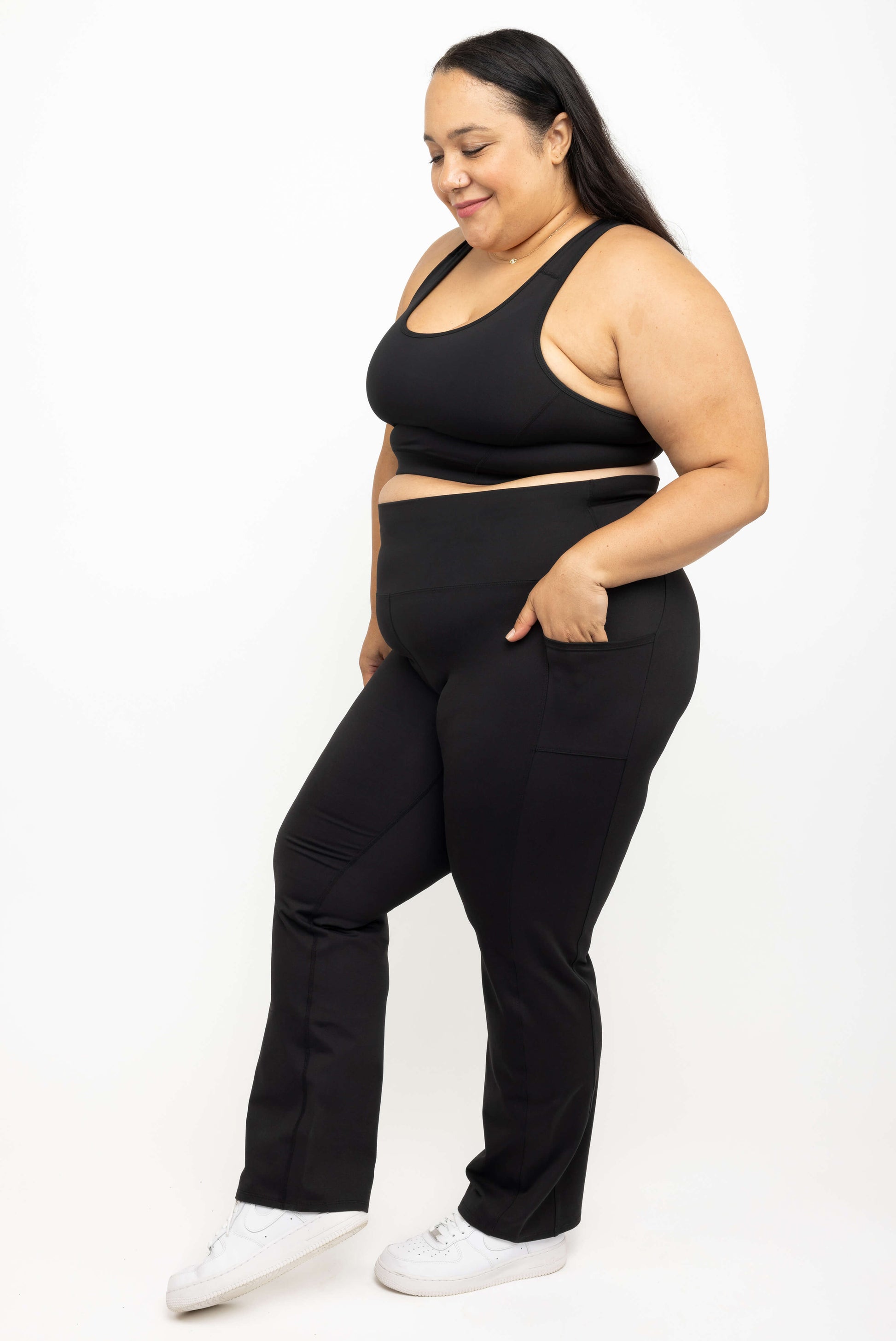 Profile view of Plus size model smiling with her hands in pockets of Superfit Hero straight legg leggings size 2X