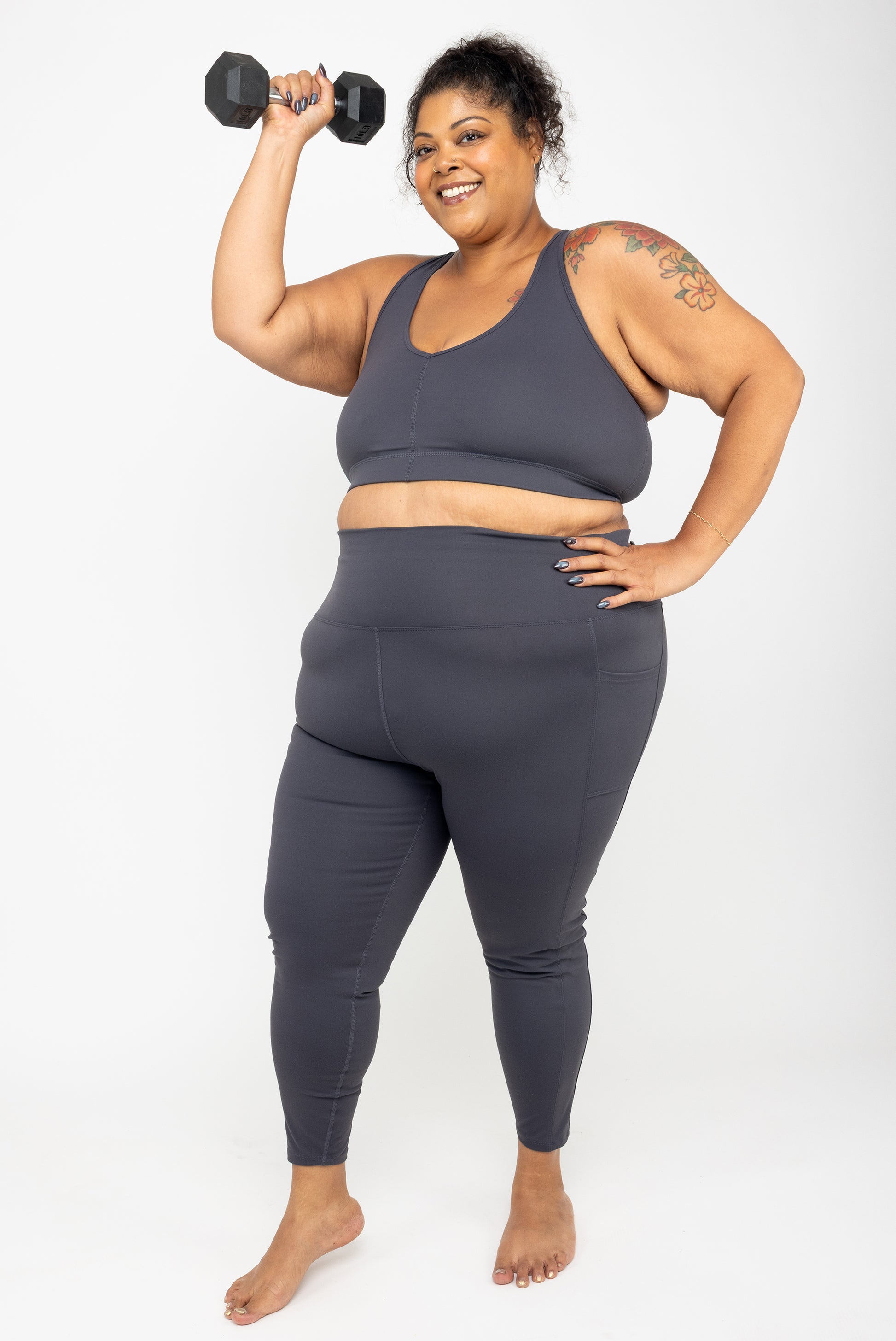 Model holding a dumbbell wearing Superfit Hero SuperHold™ 7/8 leggings in color Carbon, size 3X