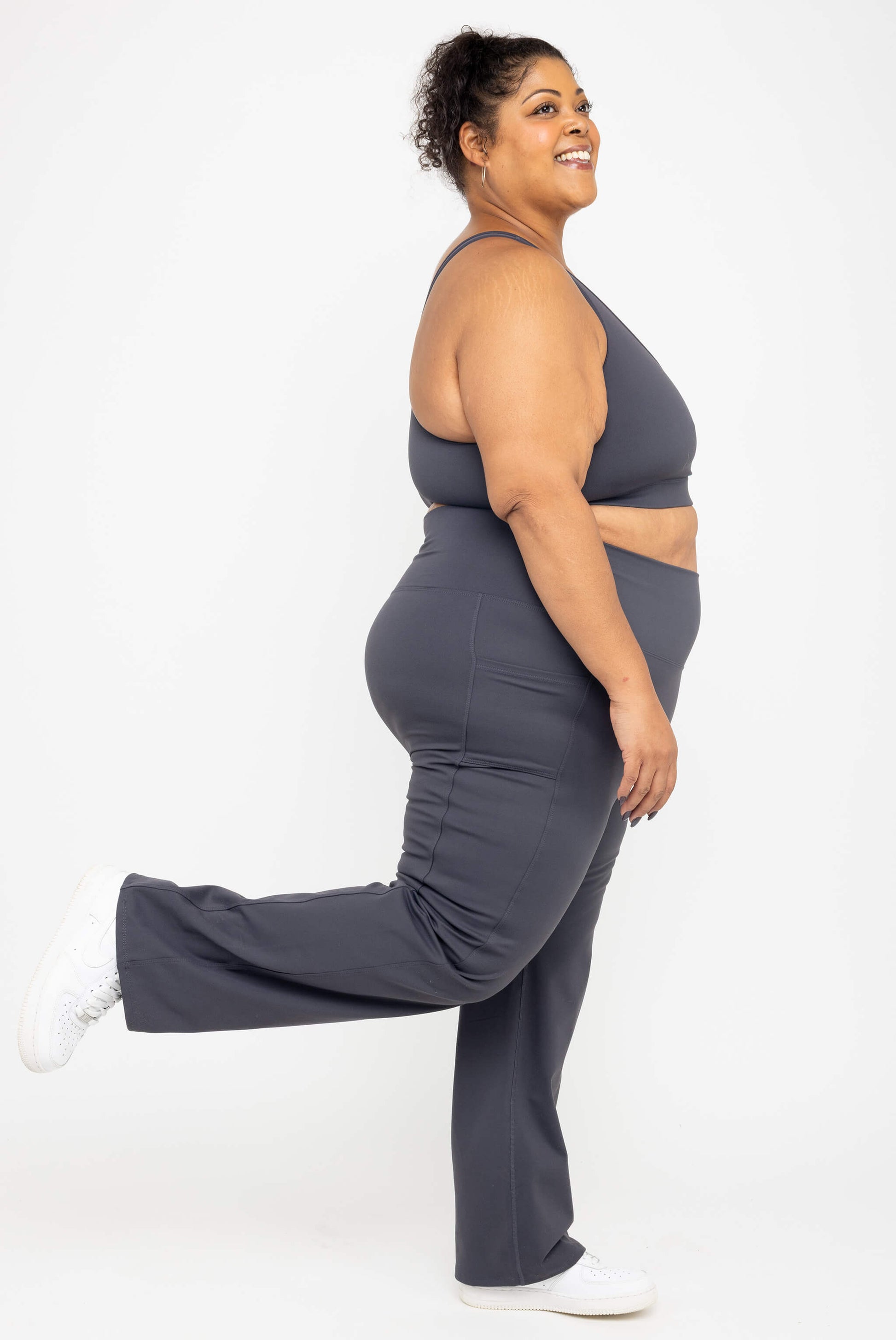 Smiling model kicking her leg back, wearing Superfit Hero SuperHold™ Straight Leggings in color Carbon, size 3X