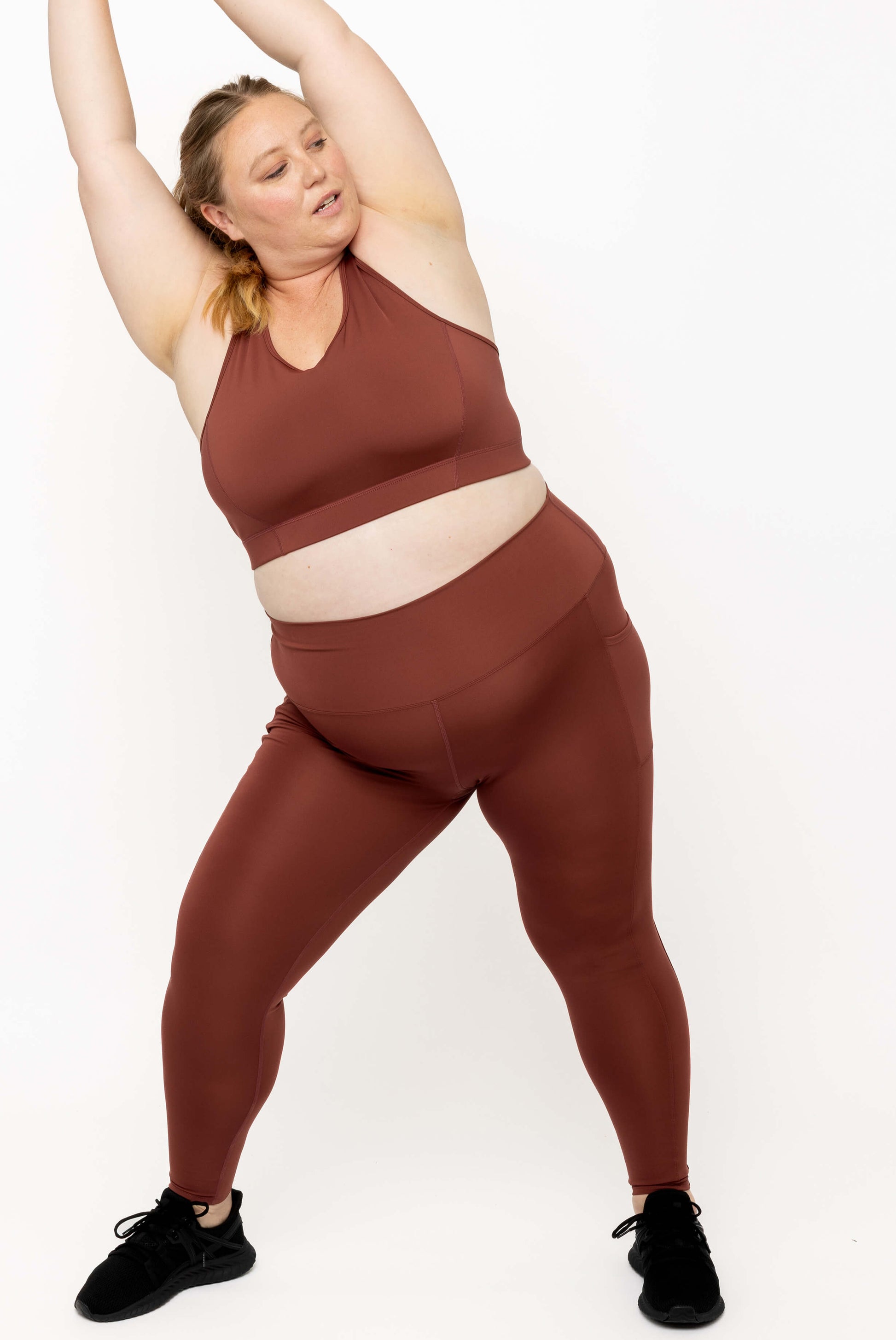Full body image of model stretching while wearing Cinnamon SuperCool leggings size 2x