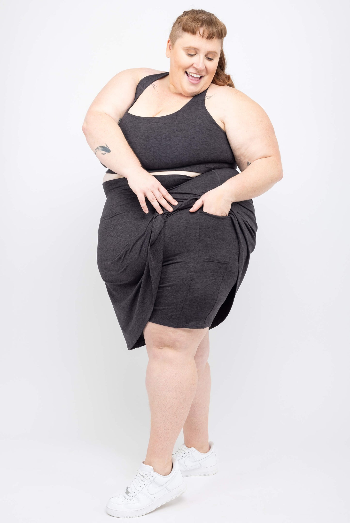 Plus size model showing off the pocket on Superfit Hero plus size skort.