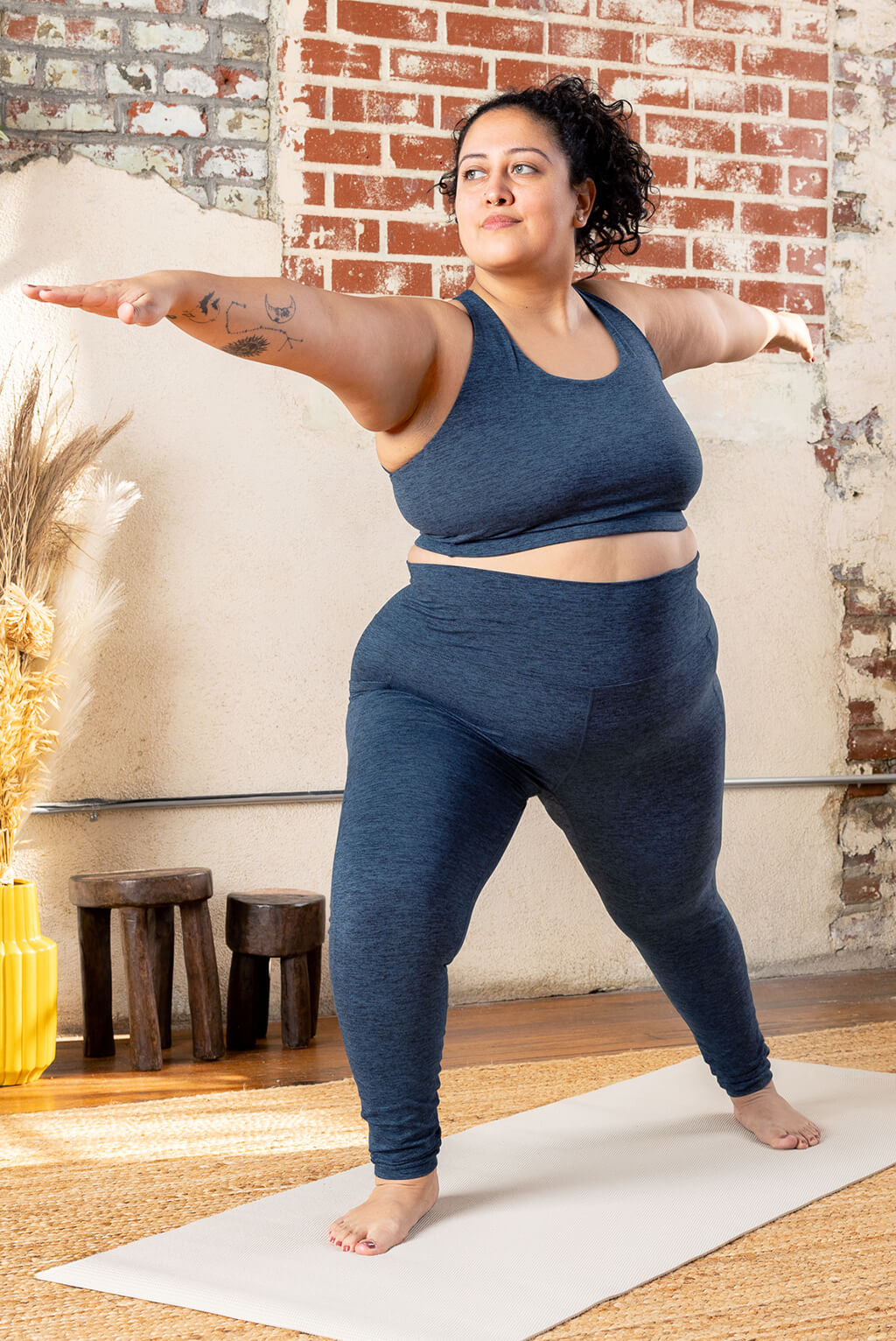 Plus size model posing in Yoga Studio wearing Superfit Hero SuperSoft skort and strappy bra in Heathered Navy