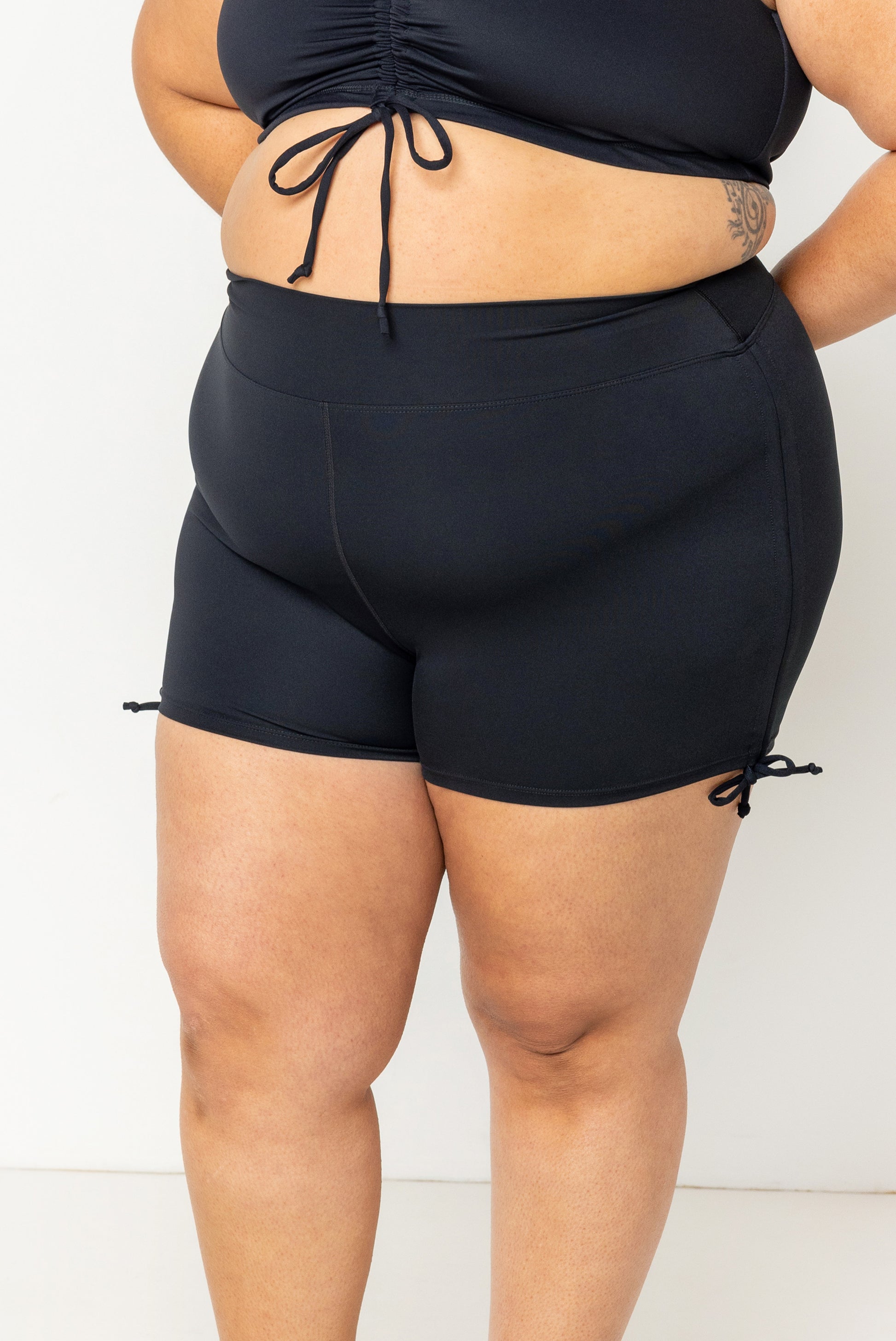 Closeup of size 2X swim plus size booty shorts with adjustable sides un-cinched. 