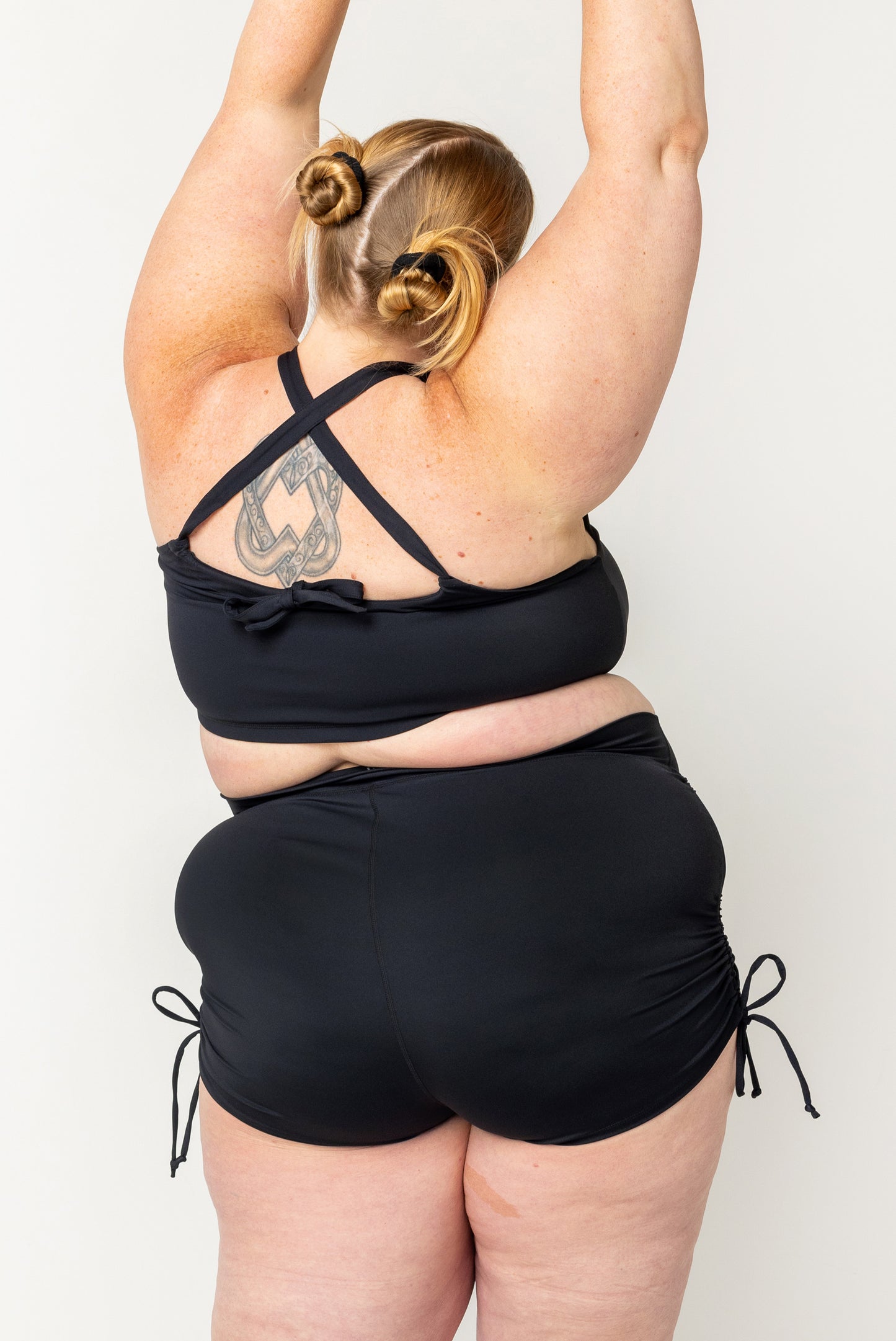 Back view of Plus size model wearing swim booty shorts with adjustable sides cinched up in size 4X.