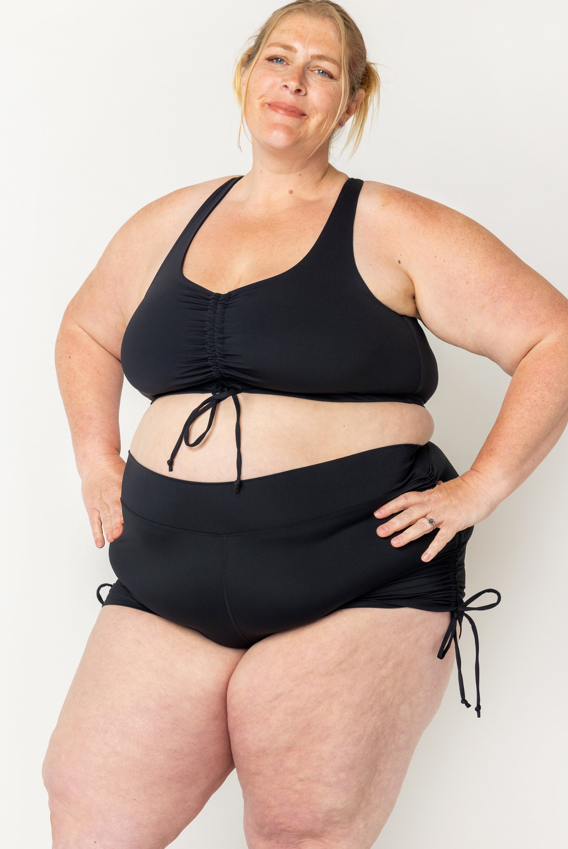 Plus size model wearing swim booty shorts with adjustable sides cinched up in size 4X.