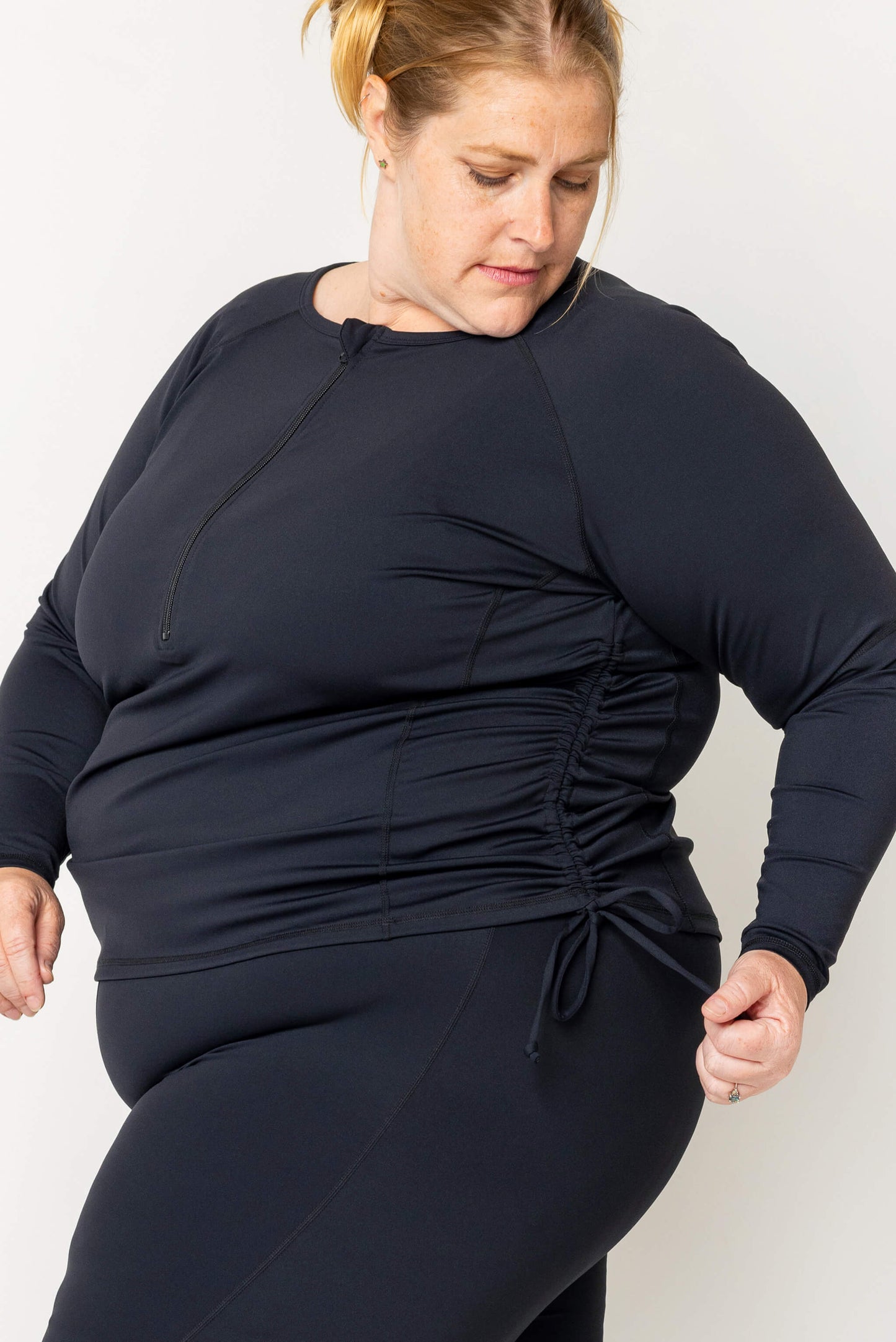 Side view of black plus size swim rash guard with adjustable sides cinched up