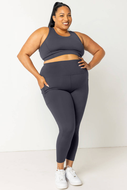 Smiling model wearing Superfit Hero SuperHold™ Carbon 7/8 leggings size 2X with hand in pocket