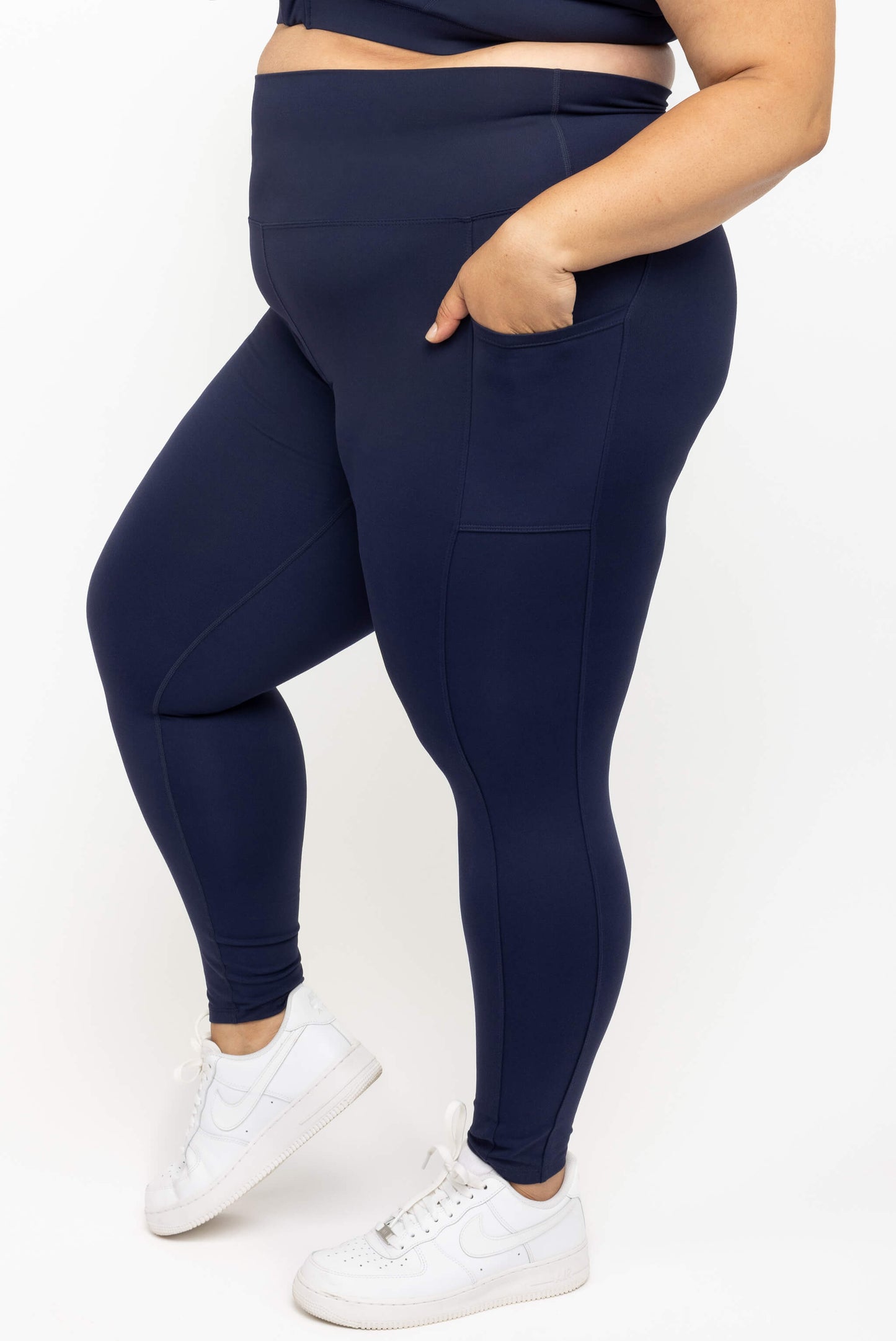 Model wearing Superfit Hero navy plus size 7/8 compression leggings with pockets size 2X profile closeup of pocket