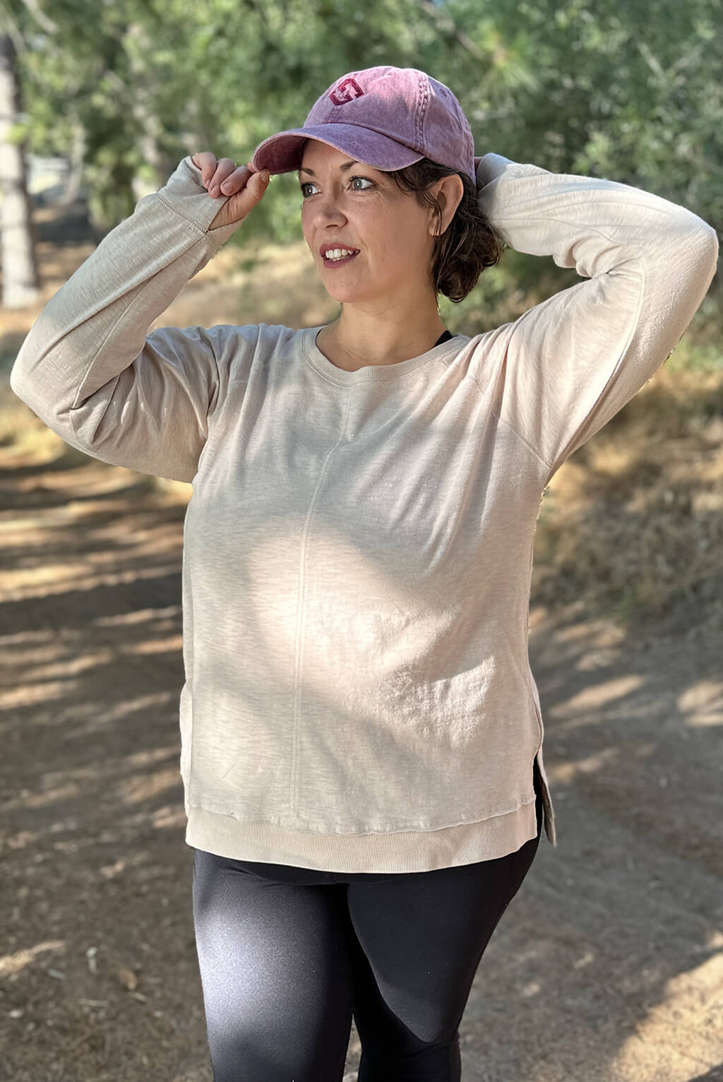 Model looks off into the distance, wearing plus size long sleeve textured top.