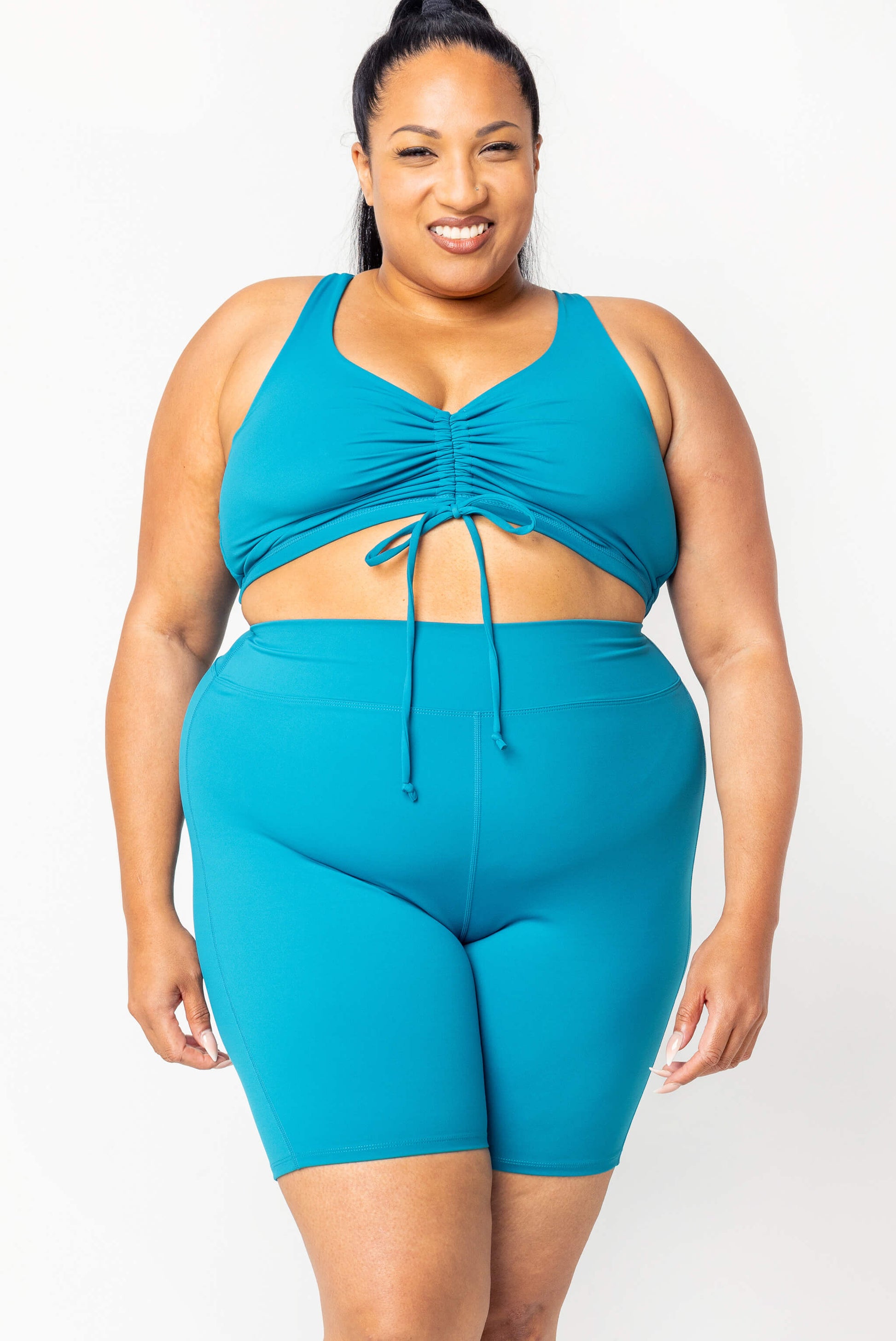 Plus size model wearing size 2X swim shorts and cinched bikini top in teal color