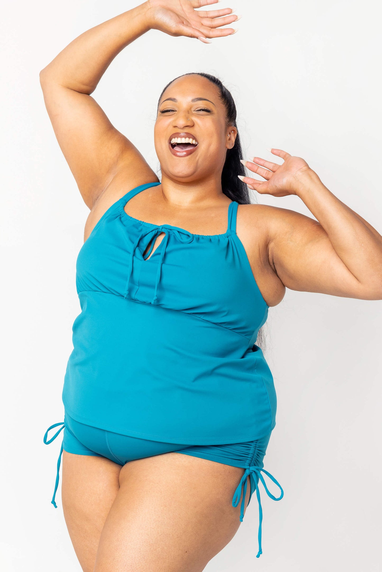 Happy plus size model wearing teal swim tankini and matching booty shorts